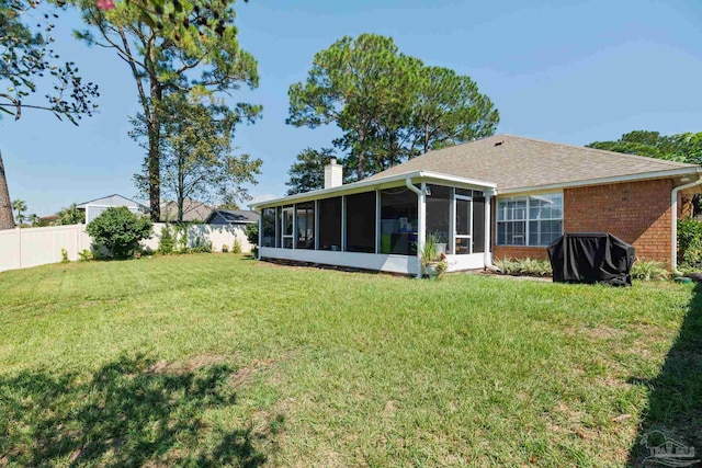 rear view of house featuring a yard and a sunroom