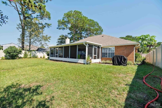 rear view of house with a yard and a sunroom