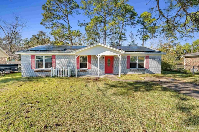 ranch-style house with a front yard, brick siding, fence, and solar panels