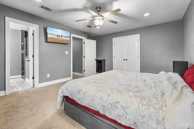 carpeted bedroom featuring ceiling fan, a closet, and ensuite bath