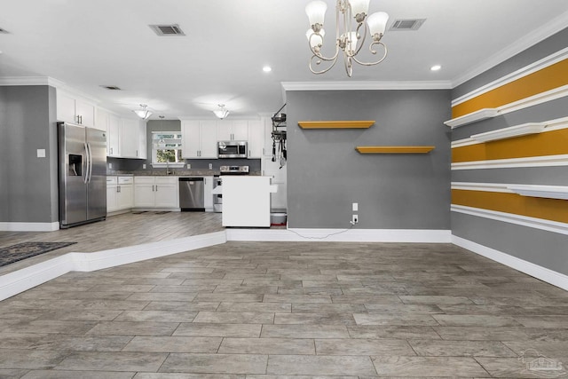 kitchen featuring a notable chandelier, appliances with stainless steel finishes, decorative light fixtures, white cabinets, and ornamental molding