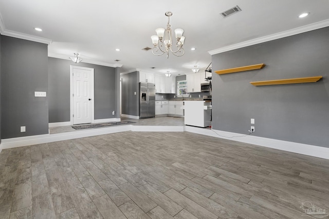 kitchen featuring pendant lighting, an inviting chandelier, white cabinets, light wood-type flooring, and stainless steel appliances