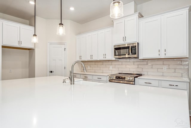 6563 Gentle Rain Dr, Milton, FL 32570 - kitchen featuring stainless steel appliances, backsplash, light countertops, hanging light fixtures, and white cabinetry