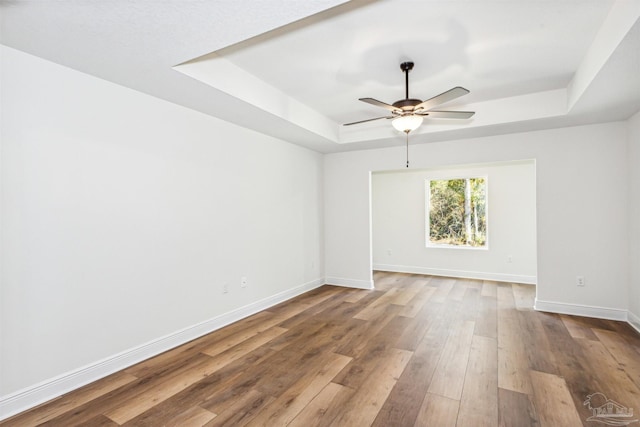 6563 Gentle Rain Dr, Milton, FL 32570 - empty room with a raised ceiling, baseboards, a ceiling fan, and wood finished floors