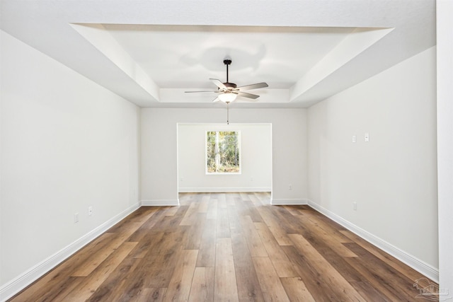 6563 Gentle Rain Dr, Milton, FL 32570 - empty room featuring a raised ceiling, a ceiling fan, wood finished floors, and baseboards