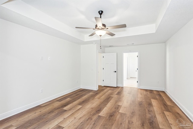 6563 Gentle Rain Dr, Milton, FL 32570 - spare room with a tray ceiling, a ceiling fan, hardwood / wood-style floors, and baseboards