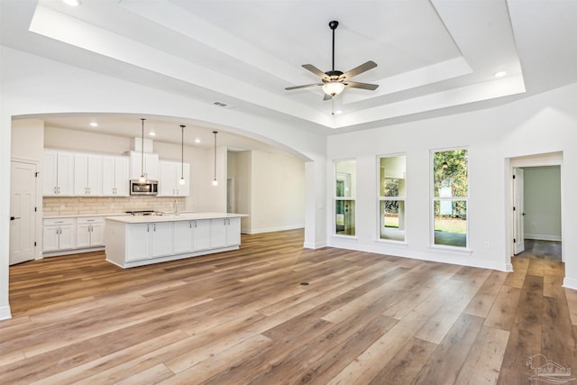 6563 Gentle Rain Dr, Milton, FL 32570 - unfurnished living room featuring a raised ceiling, a ceiling fan, arched walkways, recessed lighting, and light wood-style flooring