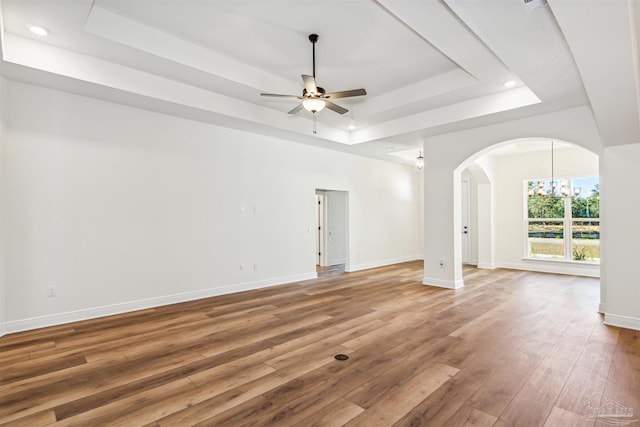 6563 Gentle Rain Dr, Milton, FL 32570 - unfurnished living room with a tray ceiling, ceiling fan, arched walkways, light wood-style floors, and baseboards