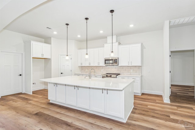 6563 Gentle Rain Dr, Milton, FL 32570 - kitchen with stainless steel appliances, tasteful backsplash, light wood finished floors, white cabinets, and recessed lighting