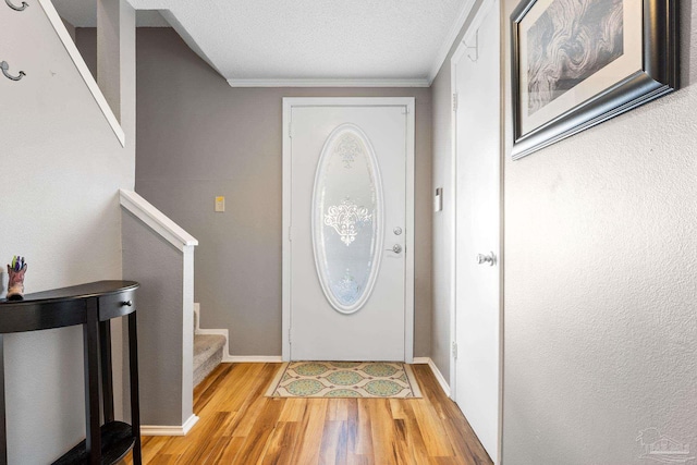 entryway with ornamental molding, light hardwood / wood-style flooring, and a textured ceiling