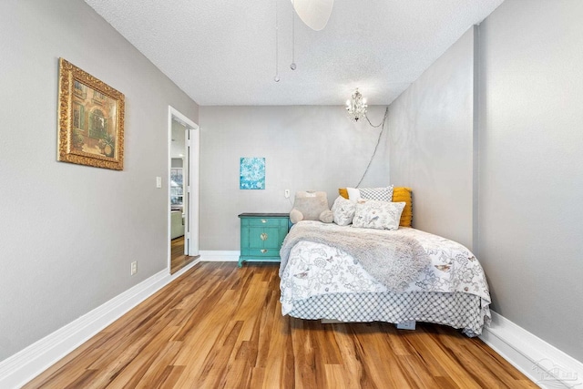 bedroom with ceiling fan, hardwood / wood-style floors, and a textured ceiling