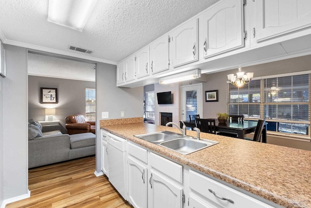 kitchen featuring white dishwasher, sink, crown molding, and white cabinetry