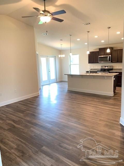 kitchen featuring an island with sink, appliances with stainless steel finishes, dark hardwood / wood-style floors, and lofted ceiling