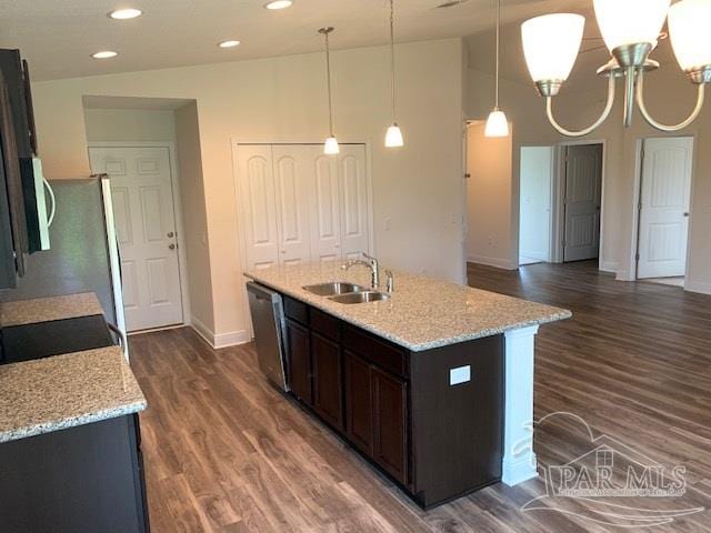 kitchen featuring lofted ceiling, sink, light stone counters, decorative light fixtures, and stainless steel appliances