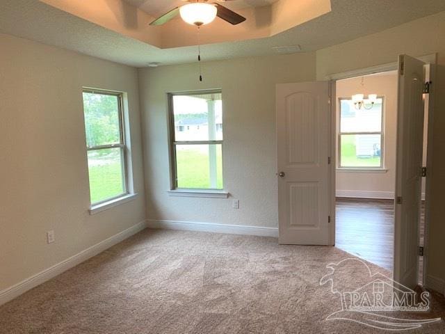 carpeted empty room featuring ceiling fan and a tray ceiling