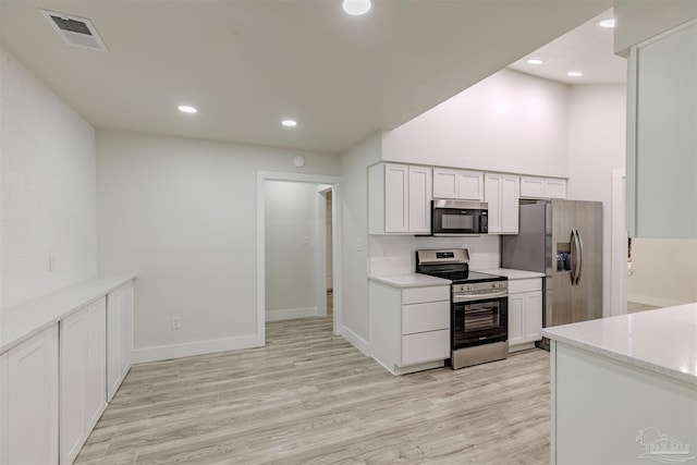 kitchen featuring light stone counters, light hardwood / wood-style flooring, white cabinets, and stainless steel appliances