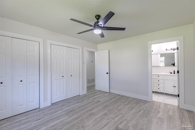 unfurnished bedroom with connected bathroom, ceiling fan, and two closets