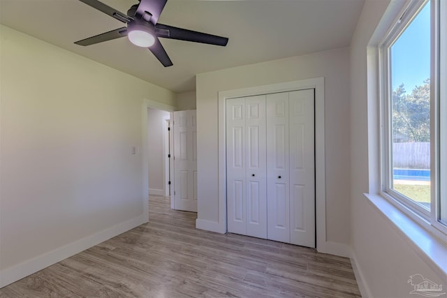 unfurnished bedroom featuring ceiling fan, a closet, and light wood-type flooring