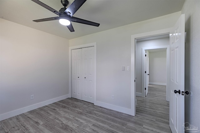 unfurnished bedroom with ceiling fan, light wood-type flooring, and a closet