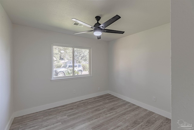 unfurnished room with ceiling fan, a textured ceiling, and light wood-type flooring