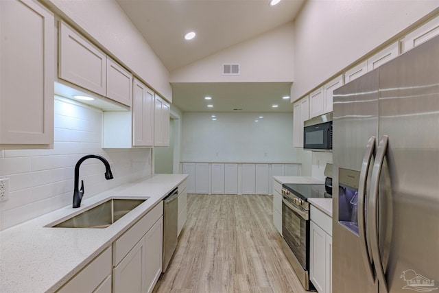 kitchen featuring light stone countertops, sink, backsplash, white cabinets, and appliances with stainless steel finishes