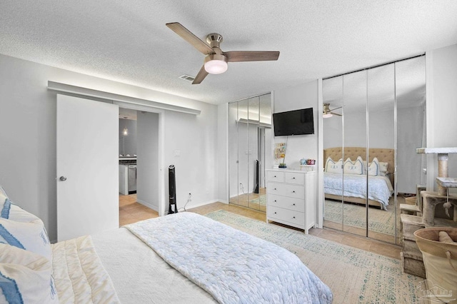 tiled bedroom featuring two closets, ceiling fan, and a textured ceiling