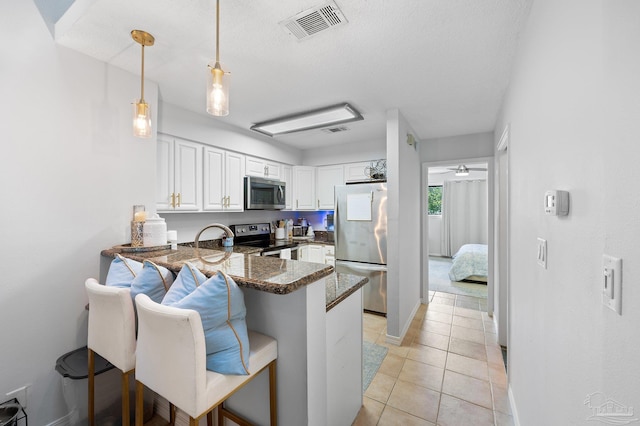 kitchen featuring stainless steel appliances, a kitchen breakfast bar, kitchen peninsula, and white cabinets