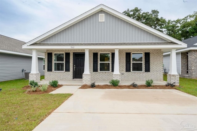 view of front of home featuring cooling unit, covered porch, and a front lawn