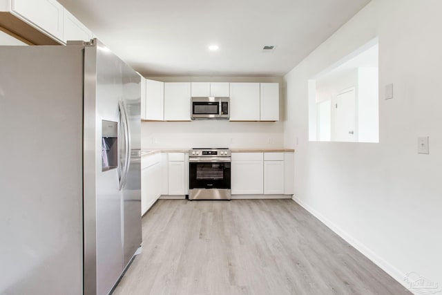 8123 Mobile Hwy, Pensacola, FL 32526 - kitchen with appliances with stainless steel finishes, light wood finished floors, white cabinetry, light countertops, and baseboards