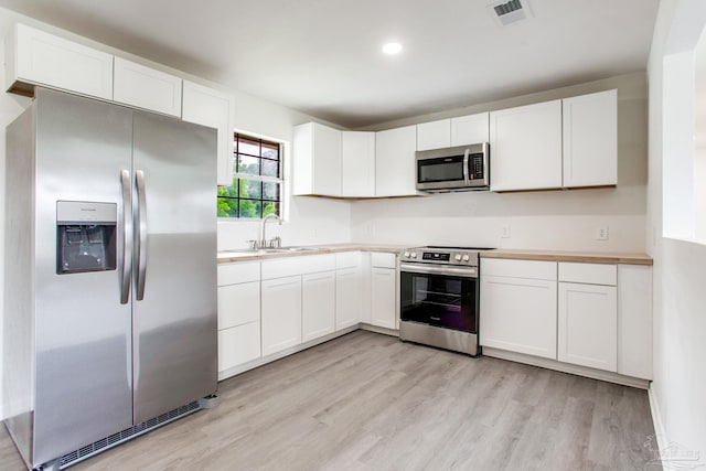 8123 Mobile Hwy, Pensacola, FL 32526 - kitchen with stainless steel appliances, a sink, light wood-type flooring, white cabinets, and light countertops