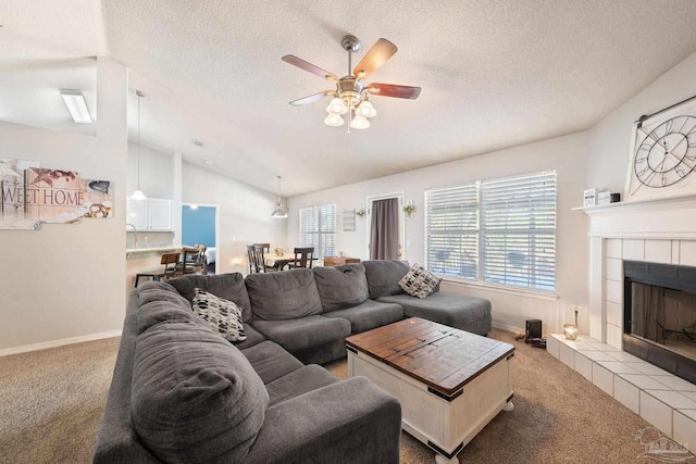 carpeted living room featuring ceiling fan, lofted ceiling, a tiled fireplace, and a textured ceiling