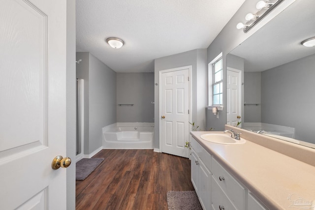 bathroom featuring a bathing tub, wood-type flooring, vanity, and a textured ceiling