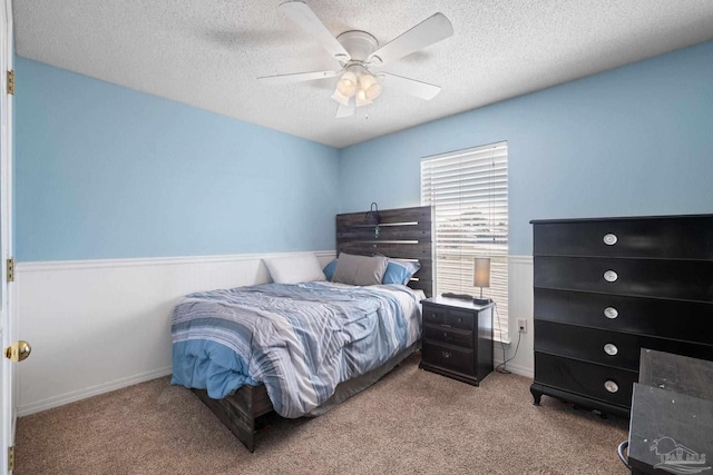 carpeted bedroom with ceiling fan and a textured ceiling