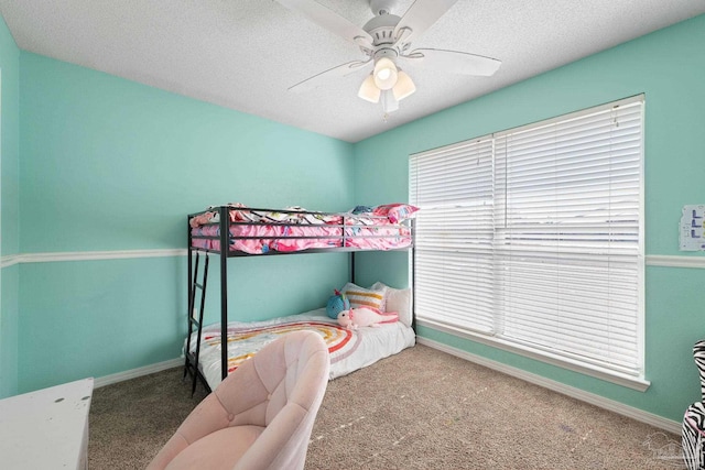 bedroom with ceiling fan, a textured ceiling, and dark colored carpet