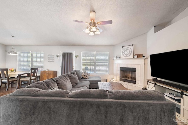 living room featuring a tile fireplace, light hardwood / wood-style floors, a textured ceiling, and a wealth of natural light