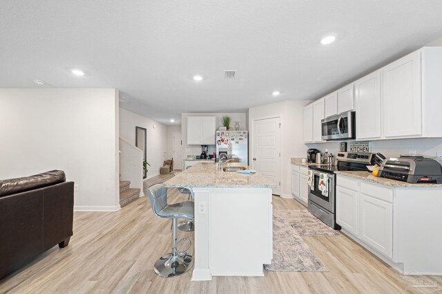 kitchen with white cabinets, a center island with sink, and appliances with stainless steel finishes