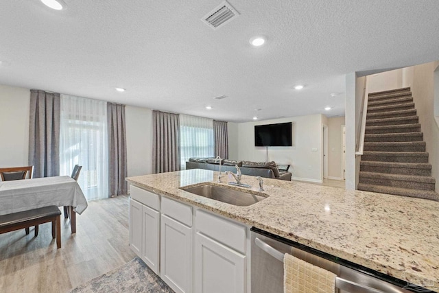 kitchen featuring dishwasher, white cabinets, sink, light hardwood / wood-style flooring, and light stone counters