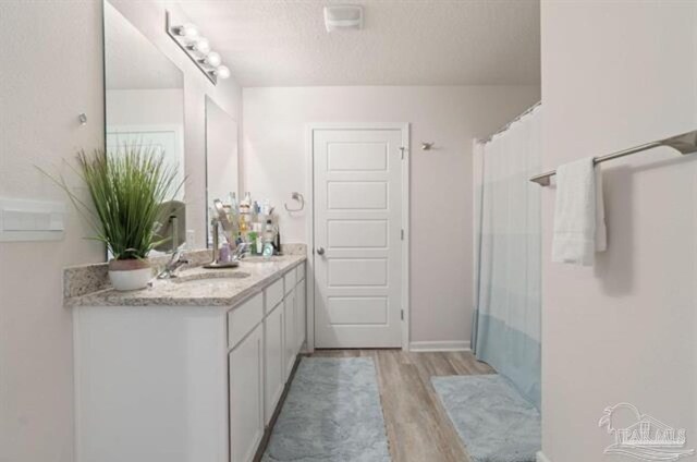 bathroom with a textured ceiling, vanity, hardwood / wood-style flooring, and walk in shower