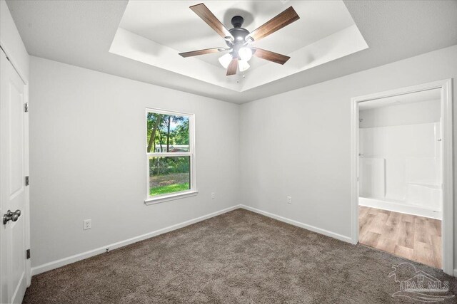 5621 Kingery Rd, Milton, FL 32583 - unfurnished bedroom featuring a tray ceiling, carpet, baseboards, ceiling fan, and connected bathroom