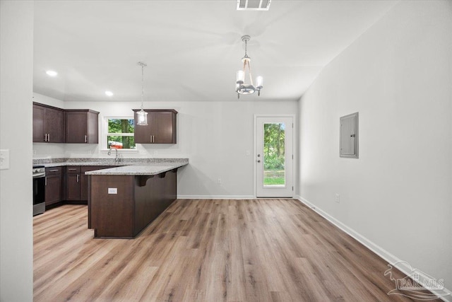 5621 Kingery Rd, Milton, FL 32583 - kitchen with dark brown cabinetry, a breakfast bar, a sink, light wood finished floors, and a peninsula