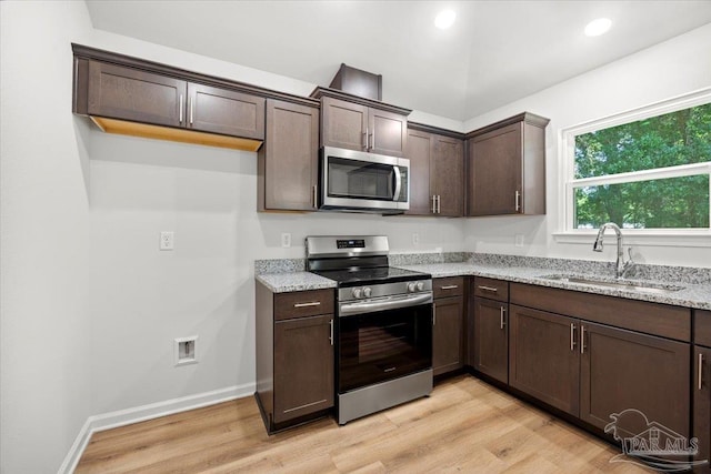 5621 Kingery Rd, Milton, FL 32583 - kitchen with stainless steel appliances, a sink, dark brown cabinetry, light stone counters, and light wood finished floors