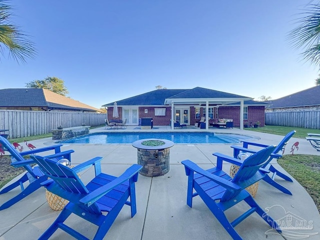 view of swimming pool with a fire pit, a patio area, pool water feature, and french doors