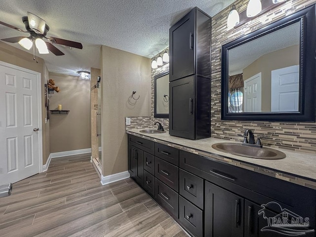 bathroom with tasteful backsplash, ceiling fan, vanity, and a textured ceiling