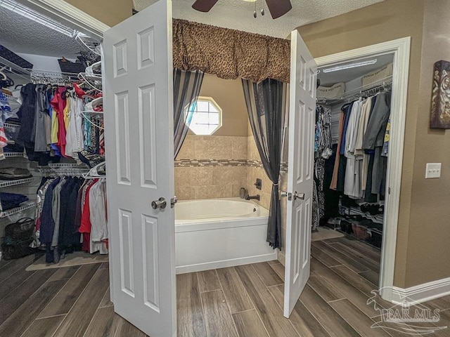 bathroom featuring a bathtub, ceiling fan, and a textured ceiling