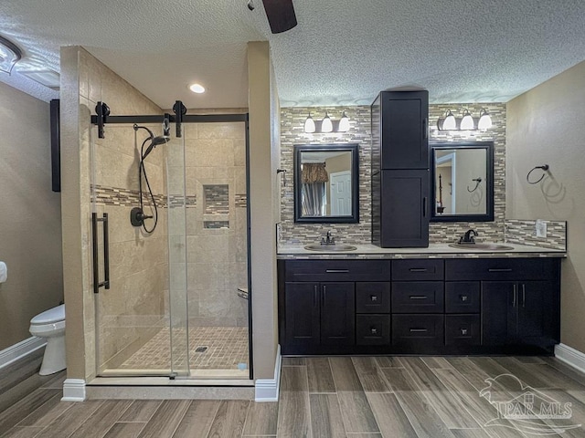 bathroom with vanity, backsplash, toilet, and an enclosed shower