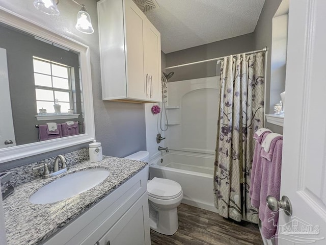 full bathroom with hardwood / wood-style floors, vanity, toilet, shower / bathtub combination with curtain, and a textured ceiling