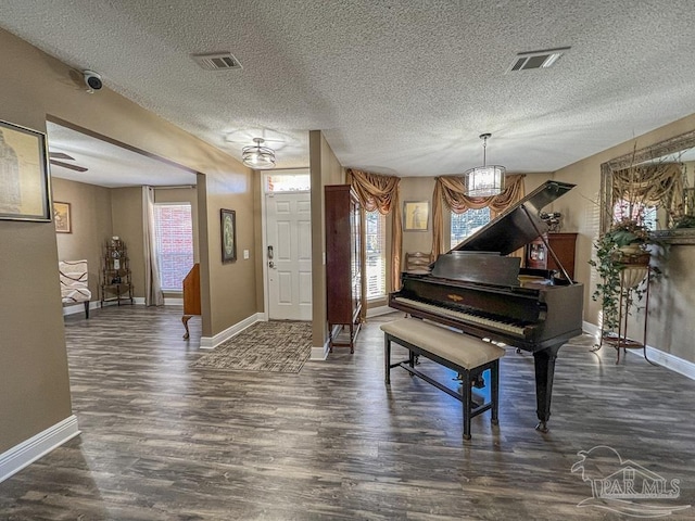 misc room with a textured ceiling, dark hardwood / wood-style flooring, and an inviting chandelier