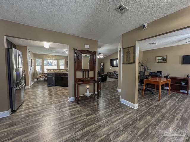 interior space featuring a textured ceiling, ceiling fan with notable chandelier, stainless steel fridge with ice dispenser, and dark wood-type flooring