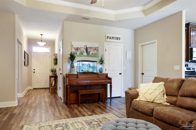 living room featuring visible vents, a raised ceiling, wood finished floors, and crown molding