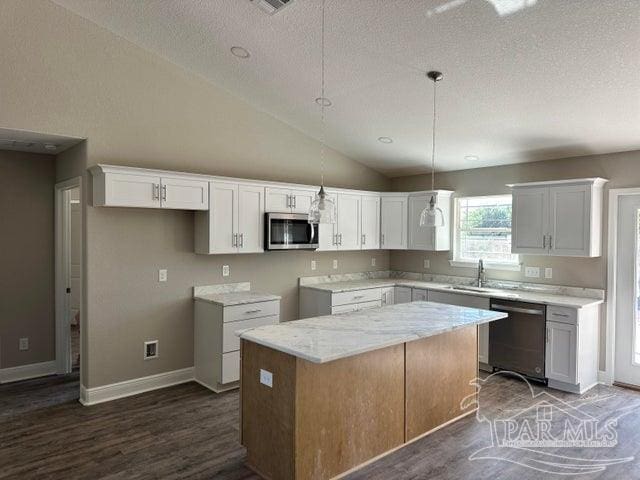 kitchen featuring lofted ceiling, white cabinets, dark hardwood / wood-style floors, appliances with stainless steel finishes, and a kitchen island